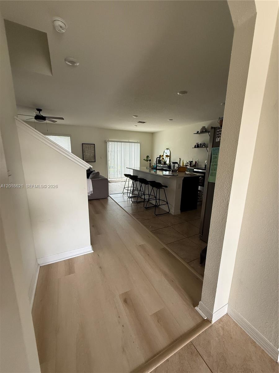 A view from a hallway into an open-concept kitchen and living area with light flooring — 1630 Reddish Egret, Davenport FL 33897, DAVENPORT, FL