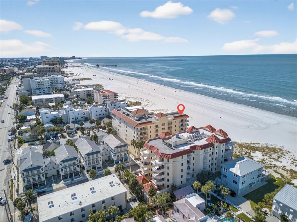 A balcony view overlooking a white sand beach and ocean at sunset with palm trees — 15 SOMERSET STREET UNIT 4A, CLEARWATER BEACH, FL