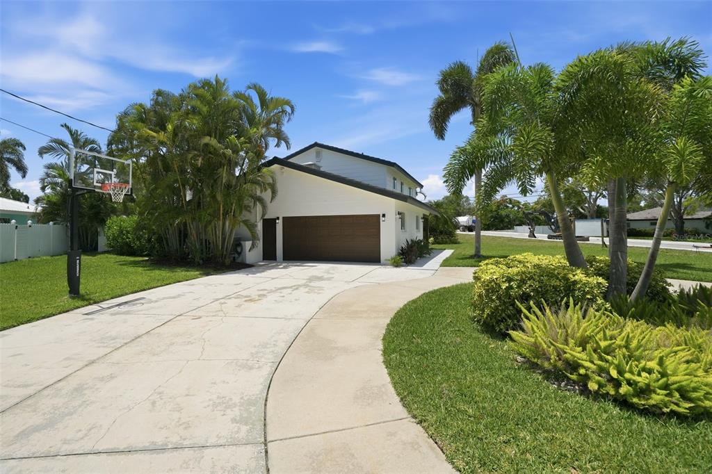 A white house with a brown garage door, a concrete driveway, and palm trees — 5101 DOVER STREET NE, ST PETERSBURG, FL