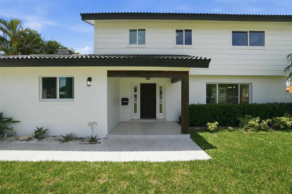 A two-story house features a white exterior, a dark front door, and a covered entryway — 5101 DOVER STREET NE, ST PETERSBURG, FL