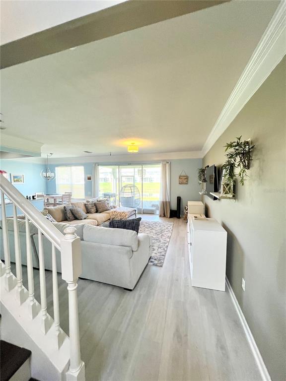 A living room features light-colored wood flooring, a large sectional sofa, and a sliding glass door — 4639 POND RIDGE DRIVE, RIVERVIEW, FL