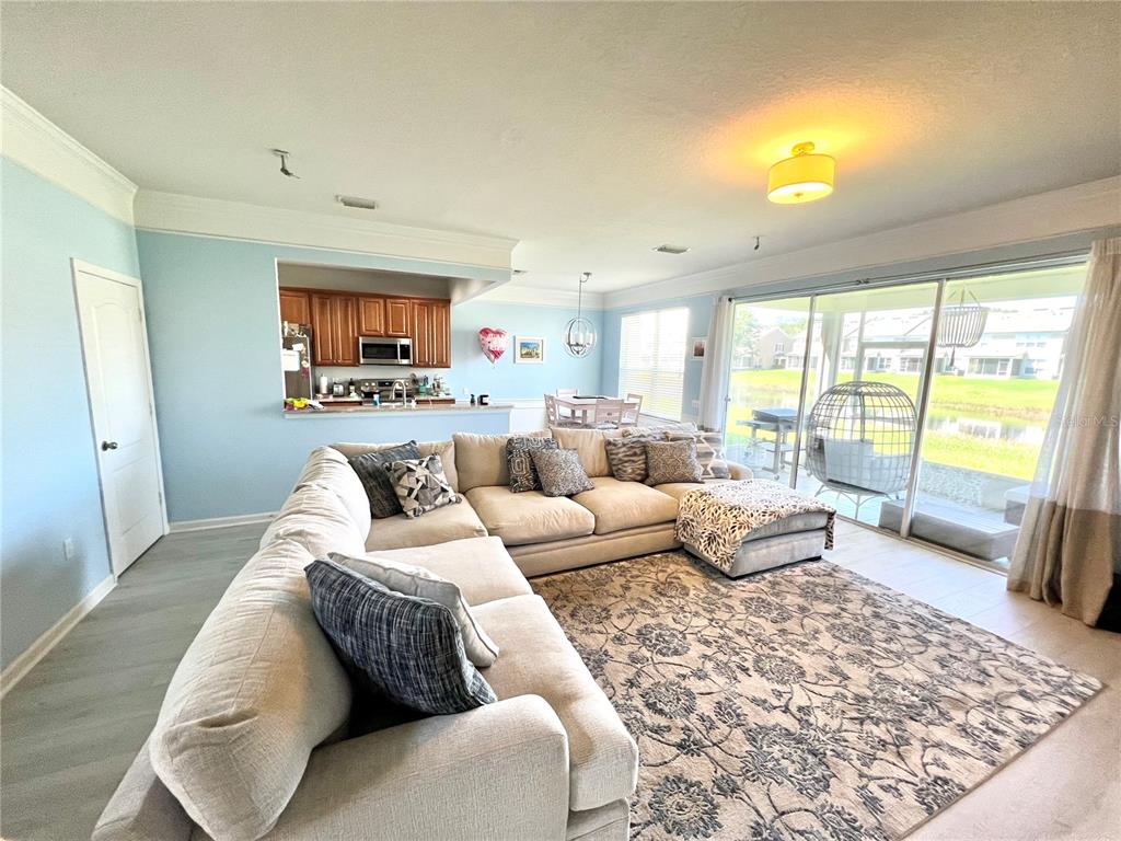 A living room with a large sectional sofa, area rug, and an open kitchen view — 4639 POND RIDGE DRIVE, RIVERVIEW, FL