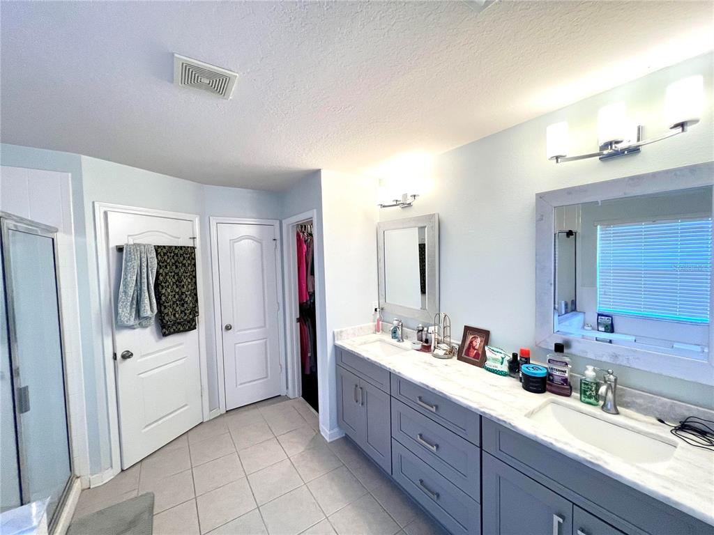 A bathroom features a double vanity with gray cabinets, marble countertops, and two mirrors — 4639 POND RIDGE DRIVE, RIVERVIEW, FL