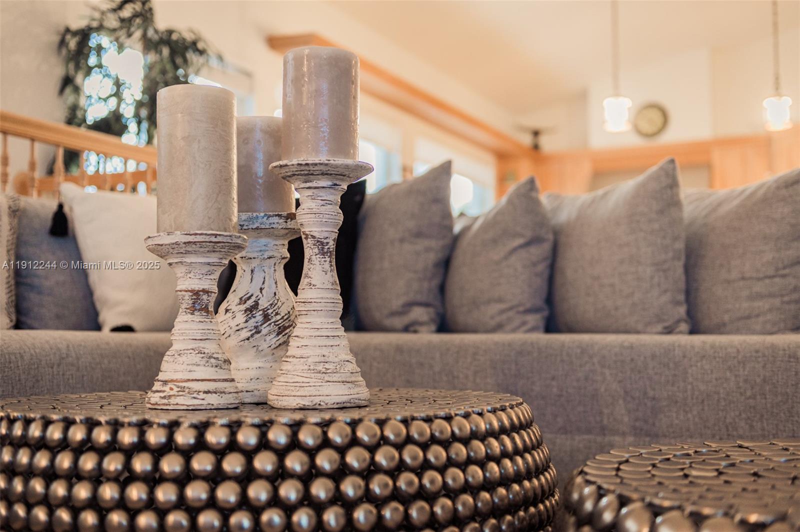 Three pillar candles on distressed wooden stands sit on a textured metal coffee table — 302 Balboa St # 0, Hollywood FL 33019, HOLLYWOOD, FL