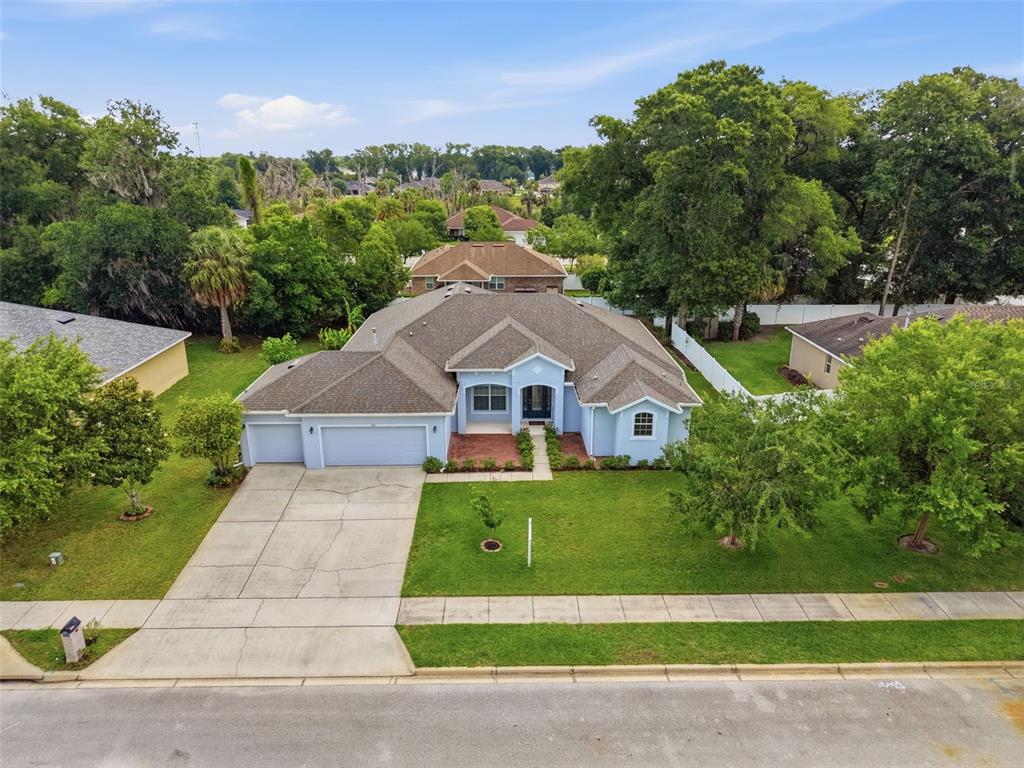 A single-story house with a light blue exterior, a three-car garage, and a front lawn — 705 OSTRICH FERN LANE, DELAND, FL