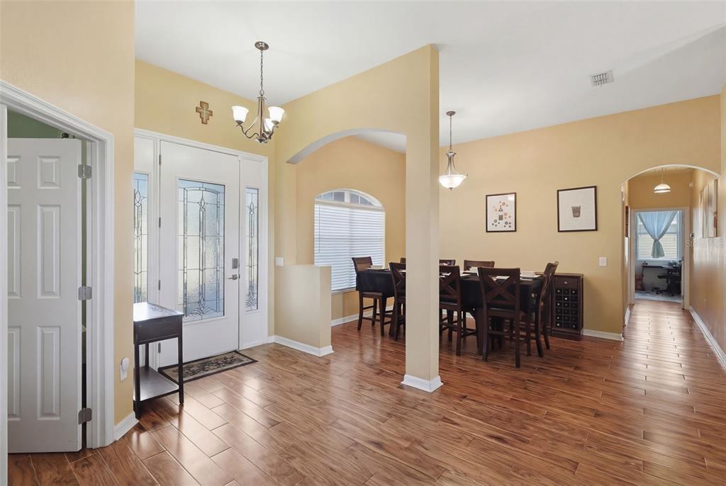 An entryway with wood-look tile flooring leads to a dining area with an arched opening — 705 OSTRICH FERN LANE, DELAND, FL