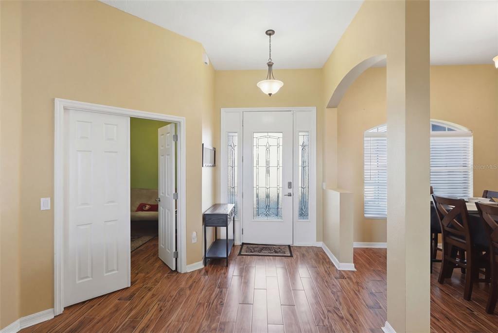 A foyer with wood-look flooring, a white front door with glass panels, and a light fixture — 705 OSTRICH FERN LANE, DELAND, FL