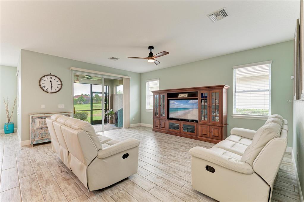 A living room features light-colored tile flooring, two white sofas, and a large wooden entertainment center — 4809 TOBERMORY WAY, BRADENTON, FL