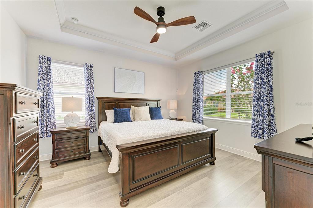 A bedroom features a wooden bed frame, matching furniture, blue patterned curtains, and light flooring — 4809 TOBERMORY WAY, BRADENTON, FL