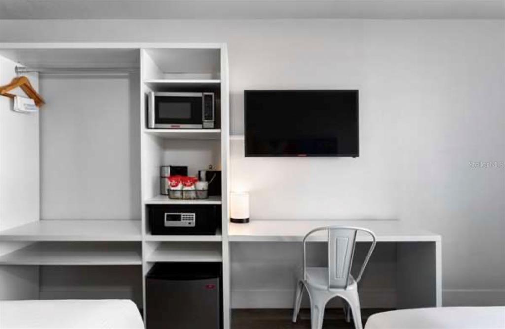 A white room features a desk, a television, a microwave, and a small refrigerator — 2930 POLYNESIAN ISLE BOULEVARD UNIT 223, KISSIMMEE, FL