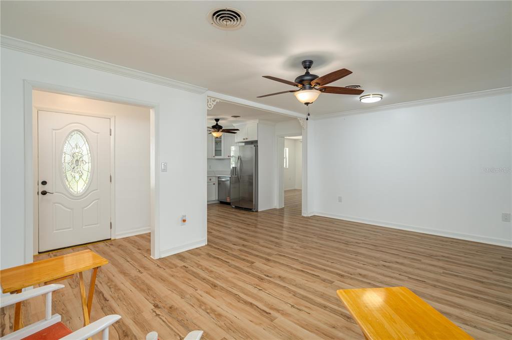 A living area with light wood-look flooring leads into a kitchen with stainless steel appliances — 2230 W HELEN CIRCLE, BARTOW, FL