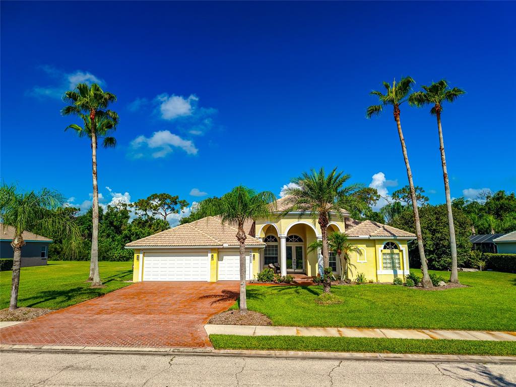 A yellow single-story house with a tiled roof, three-car garage, and several palm trees — 14711 2ND AVENUE CIRCLE NE, BRADENTON, FL