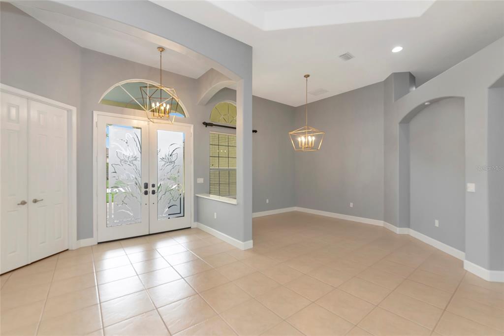 An entryway with tile flooring, a double glass front door, and a formal dining area — 14711 2ND AVENUE CIRCLE NE, BRADENTON, FL