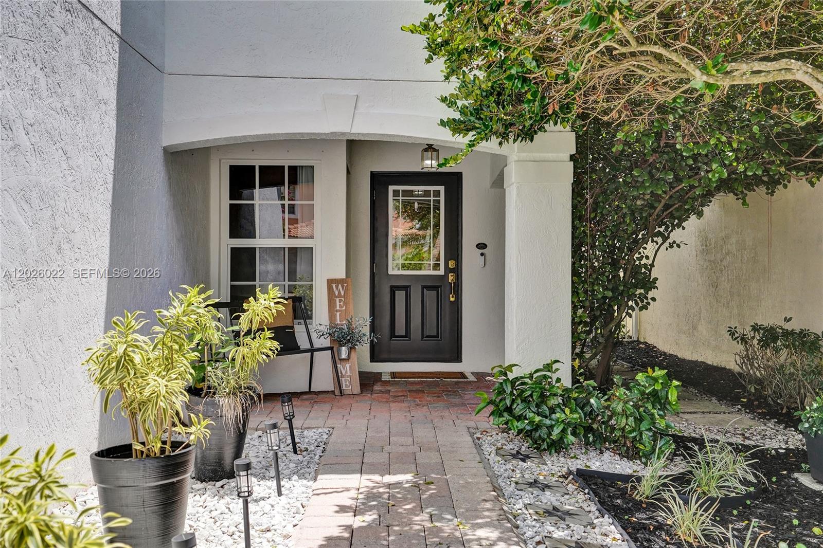 A brick walkway leads to a black front door under a covered entryway — 11953 Donlin Dr, Wellington FL 33414, WELLINGTON, FL
