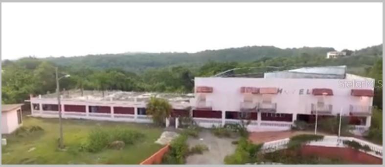 An aerial view of a two-story hotel building surrounded by trees and hilly terrain — 307 PEDERNALES WARD, CABO ROJO, PR
