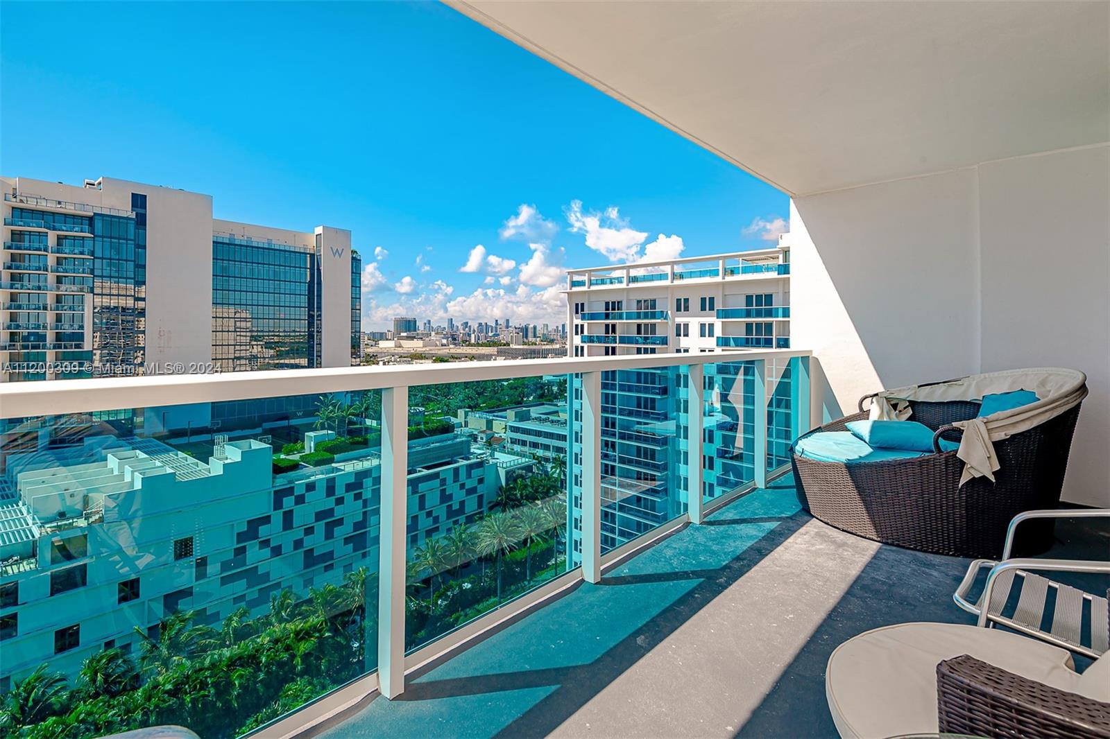 A balcony with a glass railing overlooks a city skyline and neighboring apartment buildings — 2301 Collins Ave # 1506, Miami Beach FL 33139, MIAMI BEACH, FL