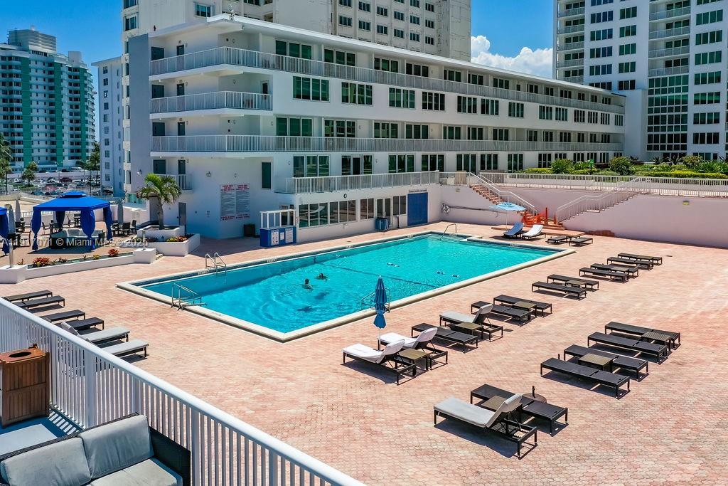 An outdoor swimming pool area features lounge chairs, a blue cabana, and a multi-story building — 5401 Collins Ave # 931, Miami Beach FL 33140, MIAMI BEACH, FL
