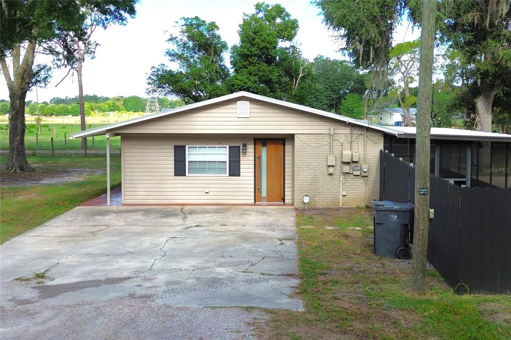 A single-story house with a beige exterior, a concrete driveway, and a wooden front door — 5009 VAUGHN ROAD, PLANT CITY, FL
