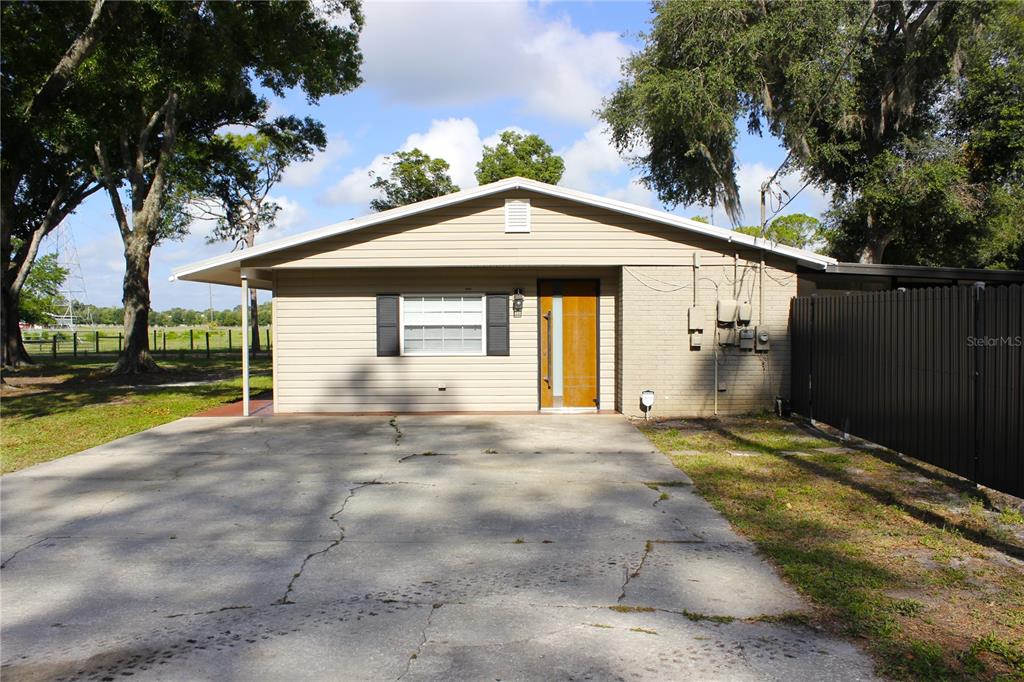 The exterior of a single-story house features beige siding, a brick section, and a concrete driveway — 5009 VAUGHN ROAD, PLANT CITY, FL