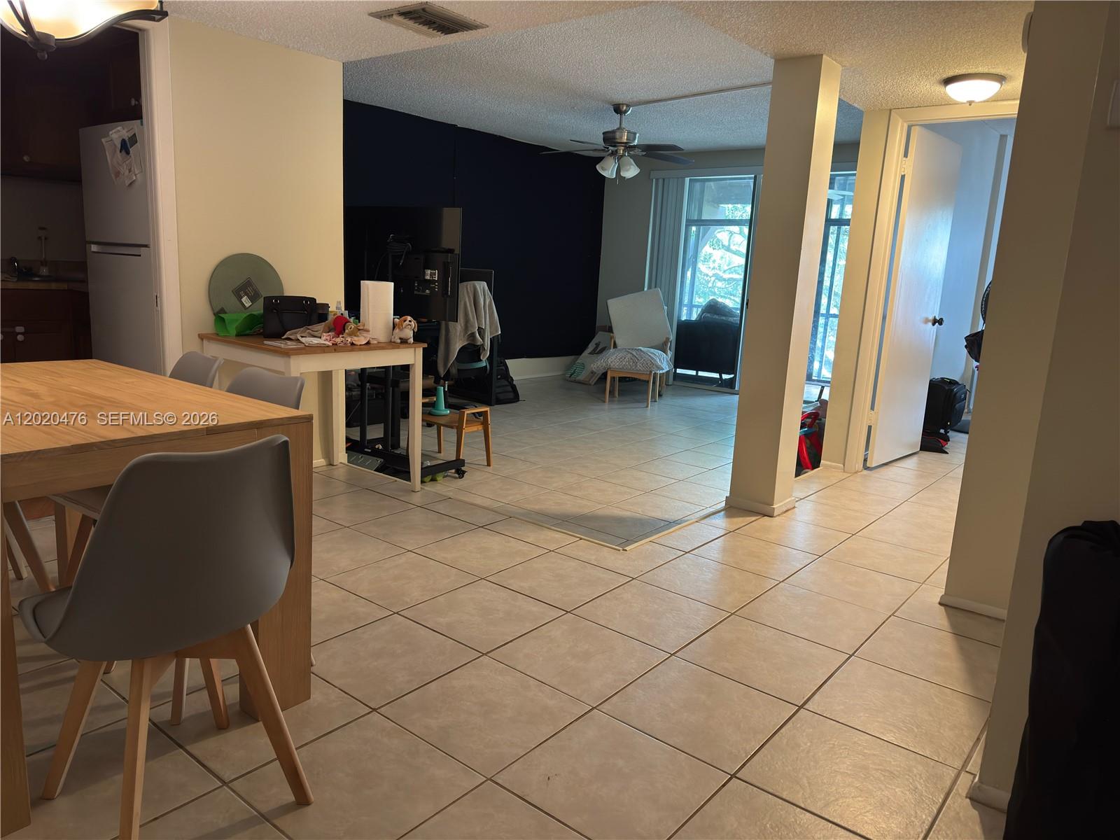 A dining area with a tiled floor leads into a living space with a ceiling fan — 3750 Inverrary Dr # 3Q, Lauderhill FL 33319, LAUDERHILL, FL