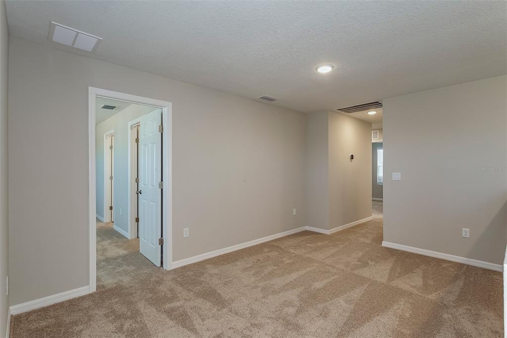 An interior view of a carpeted room with beige walls and a doorway leading elsewhere — 5460 SAN PIETRO DRIVE, WINTER HAVEN, FL
