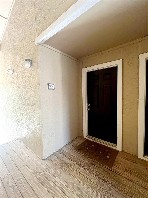 An exterior view of a residential unit entrance with a dark door and wood flooring — 4069 CROCKERS LAKE BOULEVARD UNIT 24, SARASOTA, FL