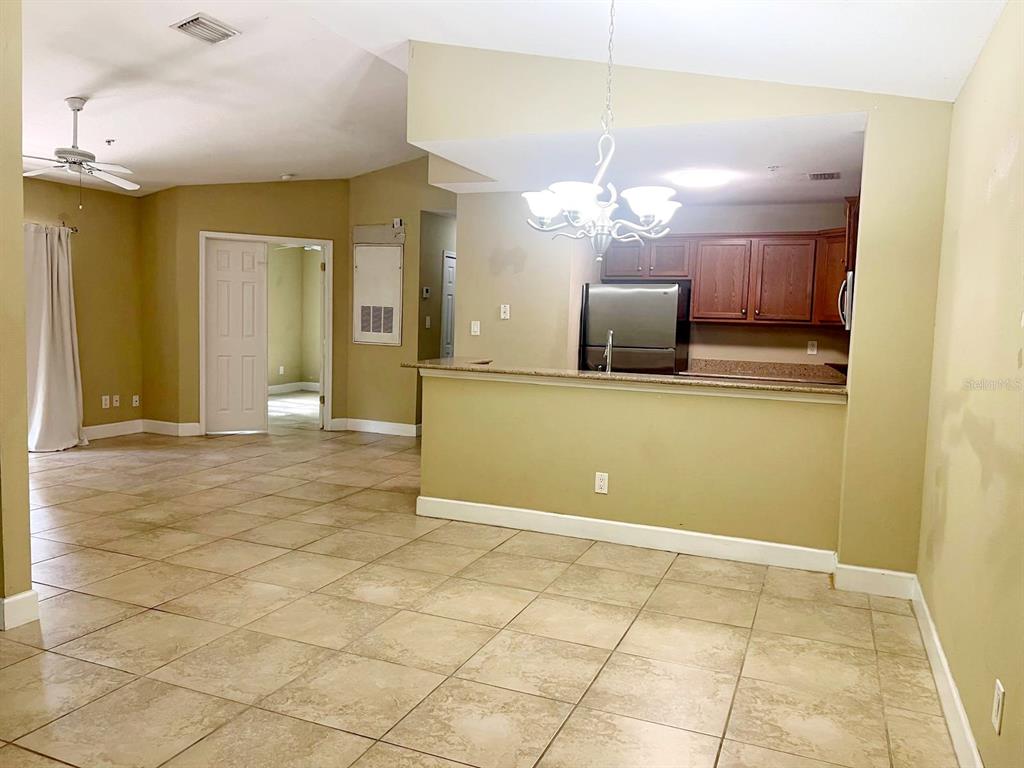 A kitchen with wood cabinets and a breakfast bar overlooks a tiled dining area — 4069 CROCKERS LAKE BOULEVARD UNIT 24, SARASOTA, FL