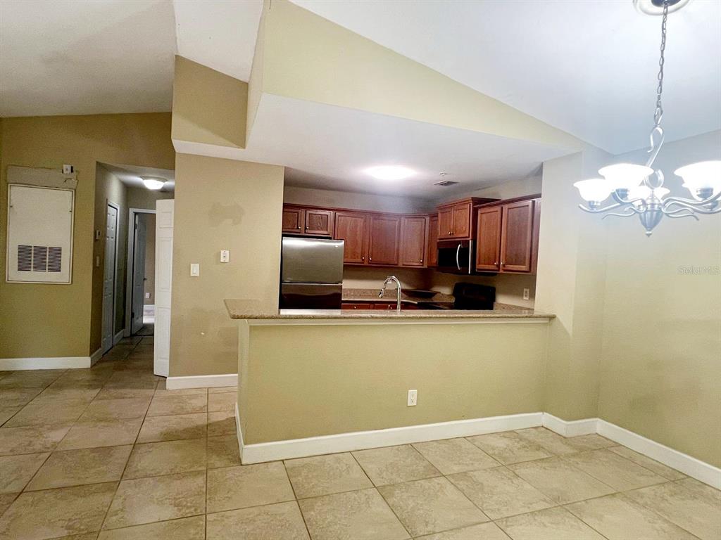 A kitchen with wood cabinets and a breakfast bar overlooks a tiled dining area — 4069 CROCKERS LAKE BOULEVARD UNIT 24, SARASOTA, FL