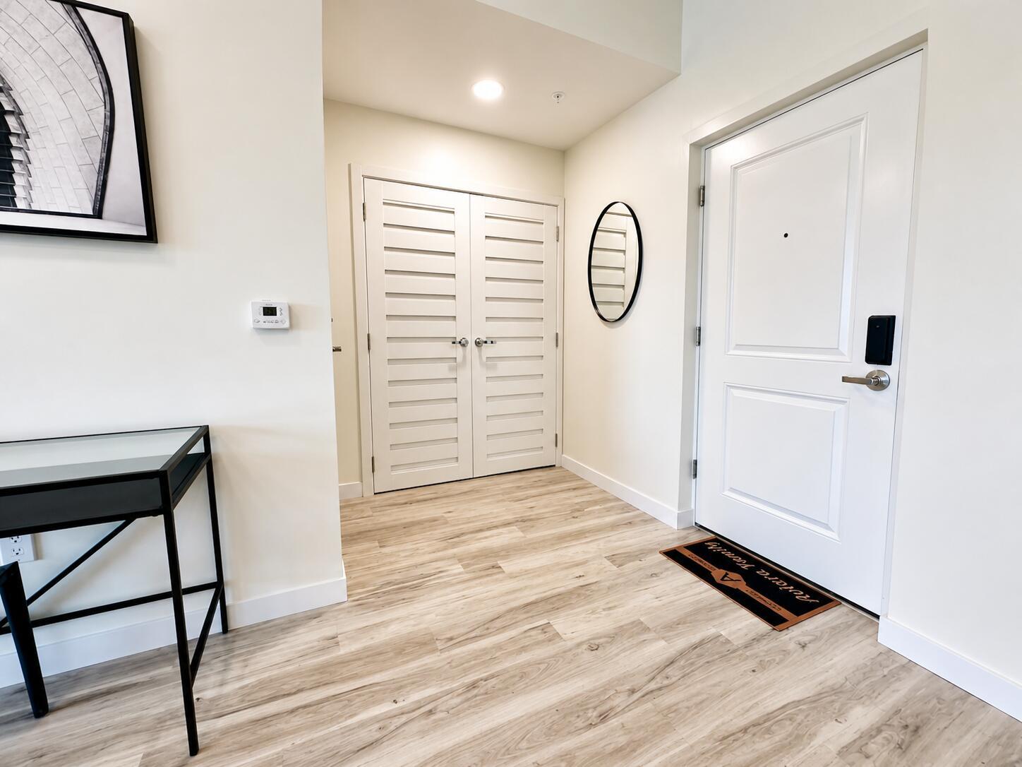 An entryway features light wood-look flooring, a white door, louvered closet doors, and a console table — 1621 S Dixie Highway # 2f, Pompano Beach FL 33060, POMPANO BEACH, FL