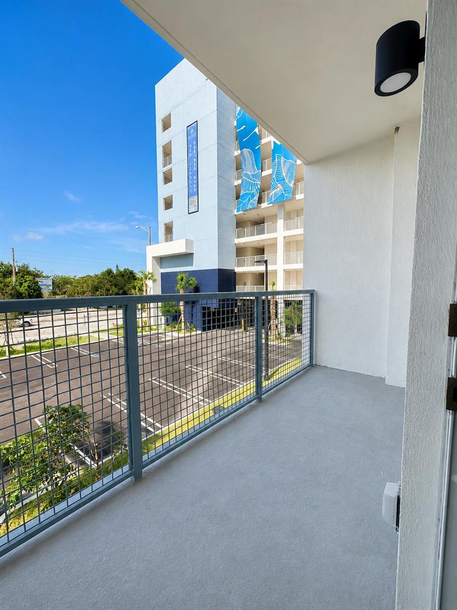A balcony with a gray floor and metal railing overlooks a parking lot and building — 1621 S Dixie Highway # 2f, Pompano Beach FL 33060, POMPANO BEACH, FL