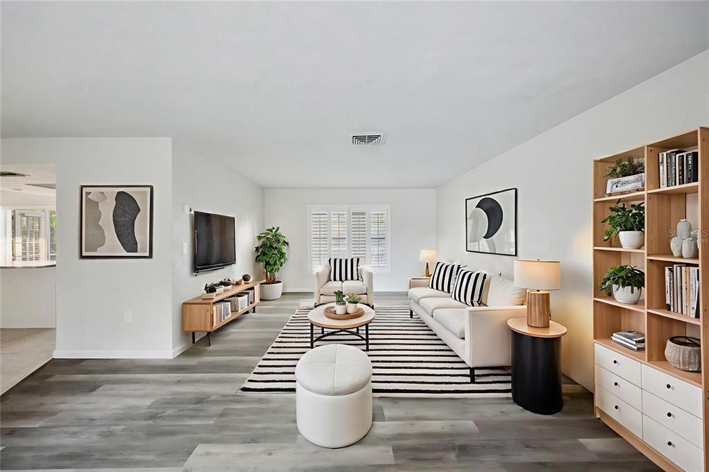 A living room features a striped rug, white sofa, armchair, and a tall wooden bookshelf — 4369 MARINE PARKWAY, NEW PORT RICHEY, FL