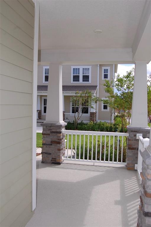 A covered front porch features white columns with stone bases and a white railing — 1827 BEACH RIDGE ROAD, CELEBRATION, FL