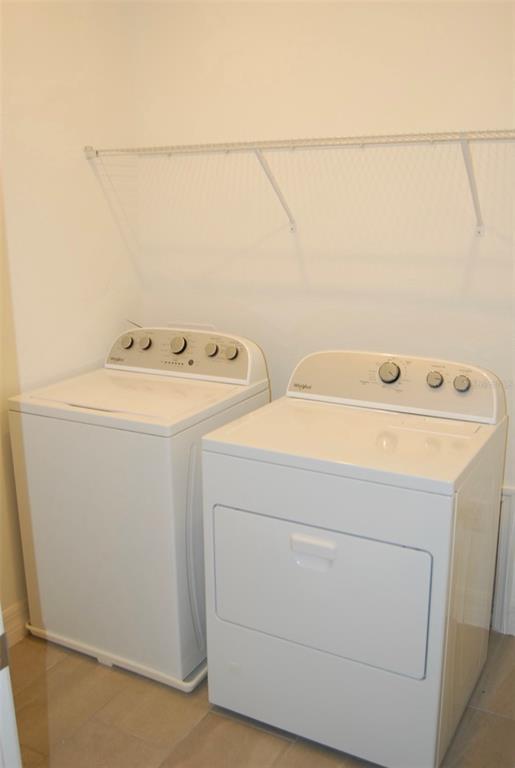 A laundry room featuring a white top-load washer and dryer beneath a wire shelf — 1827 BEACH RIDGE ROAD, CELEBRATION, FL
