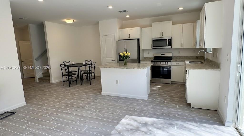 A kitchen with white cabinets, stainless steel appliances, and a central island with seating — 1019 SE 24th Ter, Homestead FL 33035, HOMESTEAD, FL