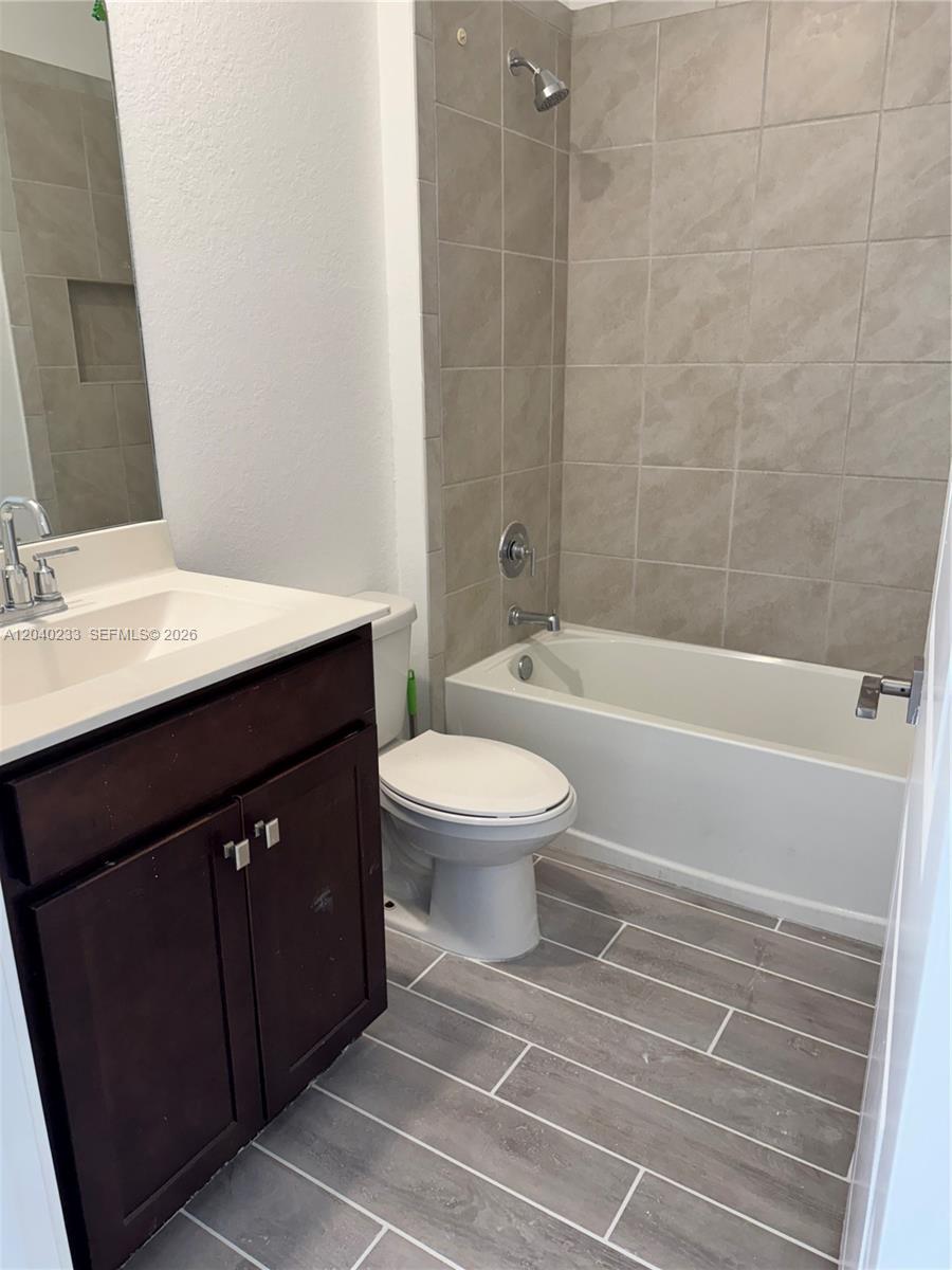 A bathroom features a dark wood vanity, a white toilet, and a tiled shower-tub combination — 1019 SE 24th Ter, Homestead FL 33035, HOMESTEAD, FL