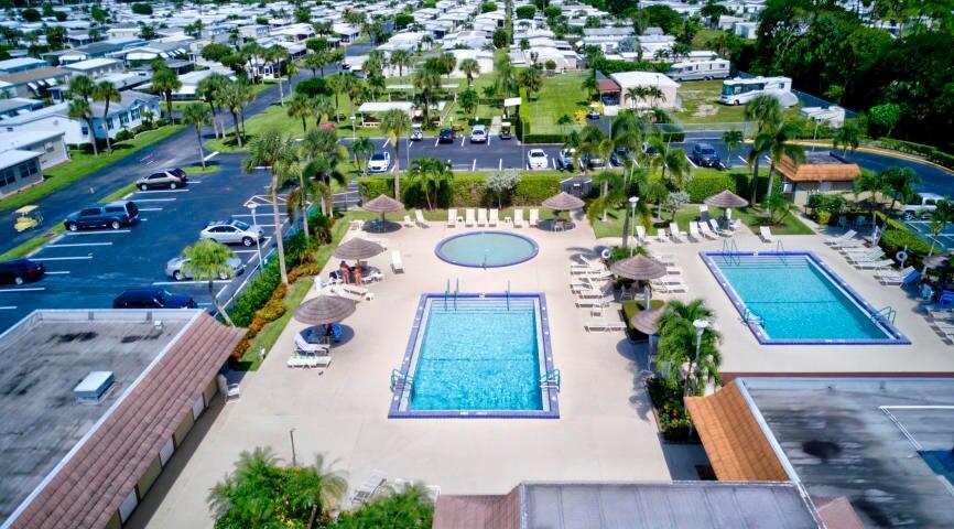 An aerial view shows a community pool area with lounge chairs and surrounding parking lots — 58009 Bahama Bay, Boynton Beach FL 33436, BOYNTON BEACH, FL