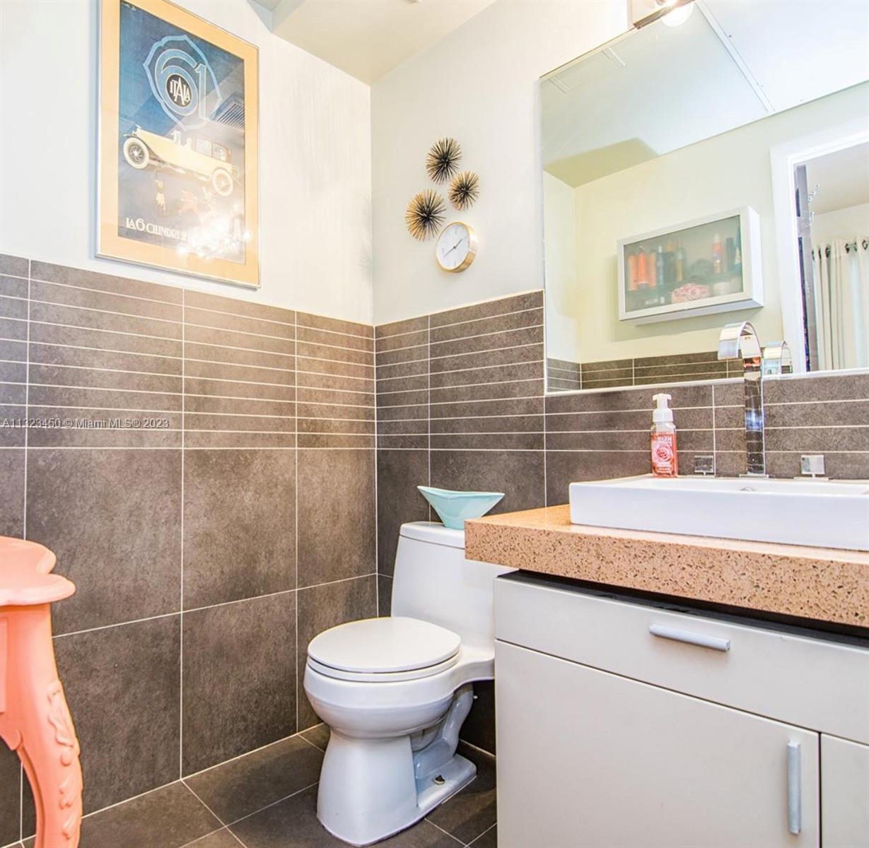 A bathroom features dark horizontal wall tiles, a white vanity, and a vessel sink — 435 21st St # 223, Miami Beach FL 33139, MIAMI BEACH, FL