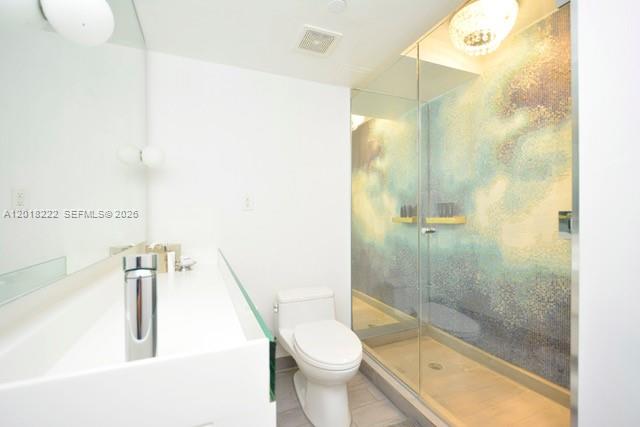 A modern bathroom features a white vanity, a toilet, and a glass-enclosed shower with mosaic tiles — 1100 West Ave # 425, Miami Beach FL 33139, MIAMI BEACH, FL