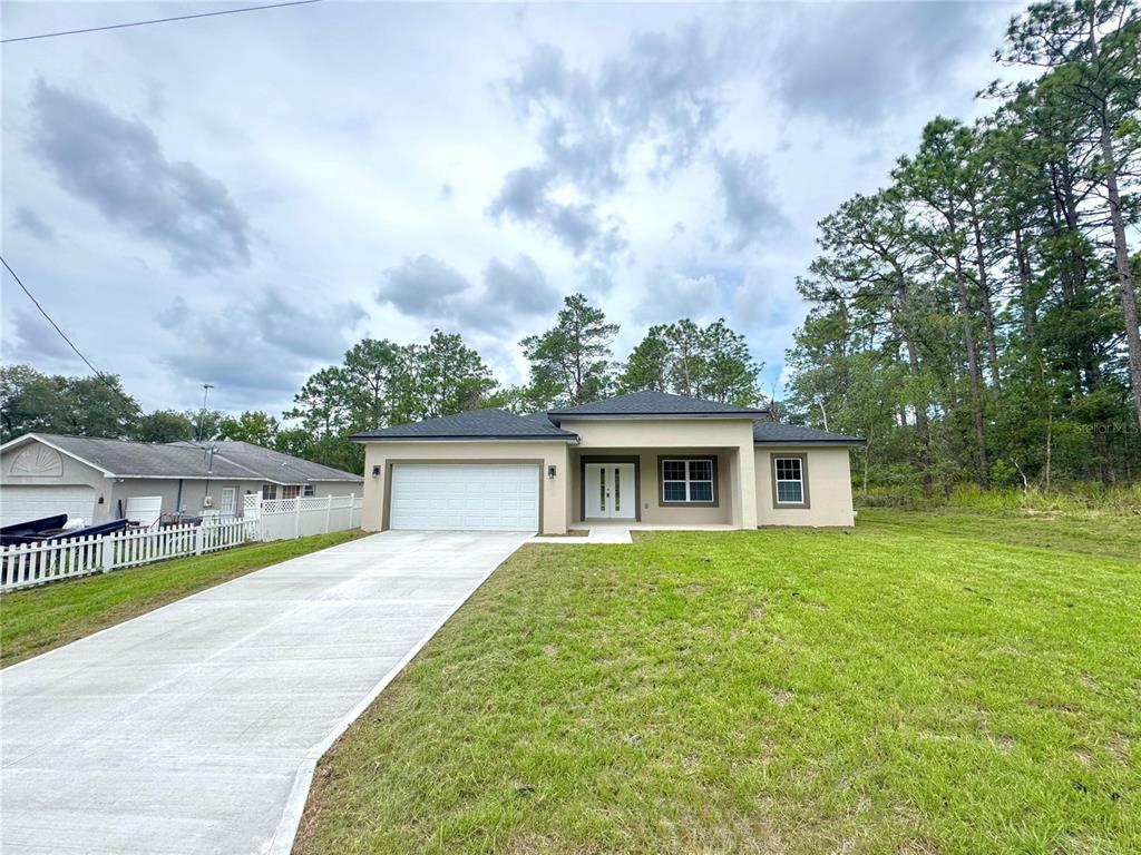 A newly constructed single-story house with a white garage, tan exterior, and a concrete driveway — 7222 N LIME DRIVE, CITRUS SPRINGS, FL