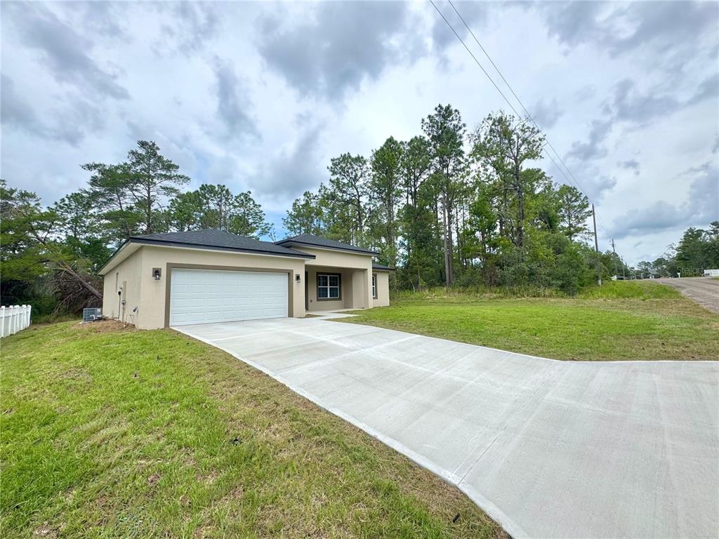 A single-story house with a white garage door and a concrete driveway sits on grass — 7222 N LIME DRIVE, CITRUS SPRINGS, FL
