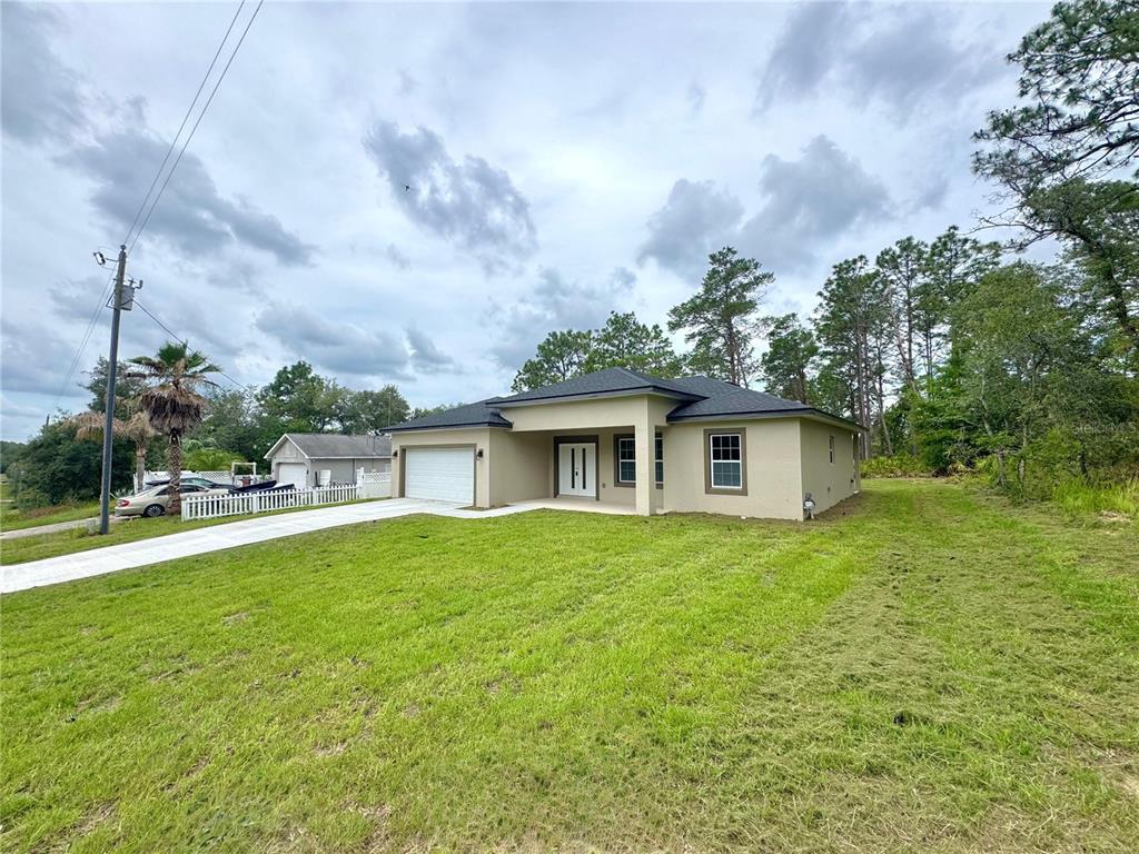 A single-story house with a tan exterior, a white garage door, and a grassy yard — 7222 N LIME DRIVE, CITRUS SPRINGS, FL