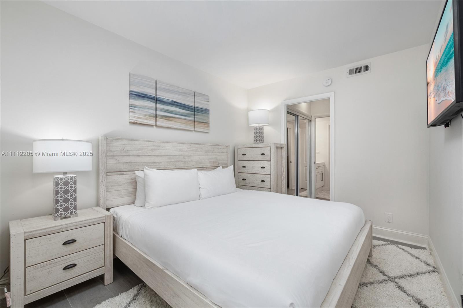 A bedroom features a light wood bed frame, matching nightstand and dresser, and white bedding — 2301 Collins Ave # 328, Miami Beach FL 33139, MIAMI BEACH, FL