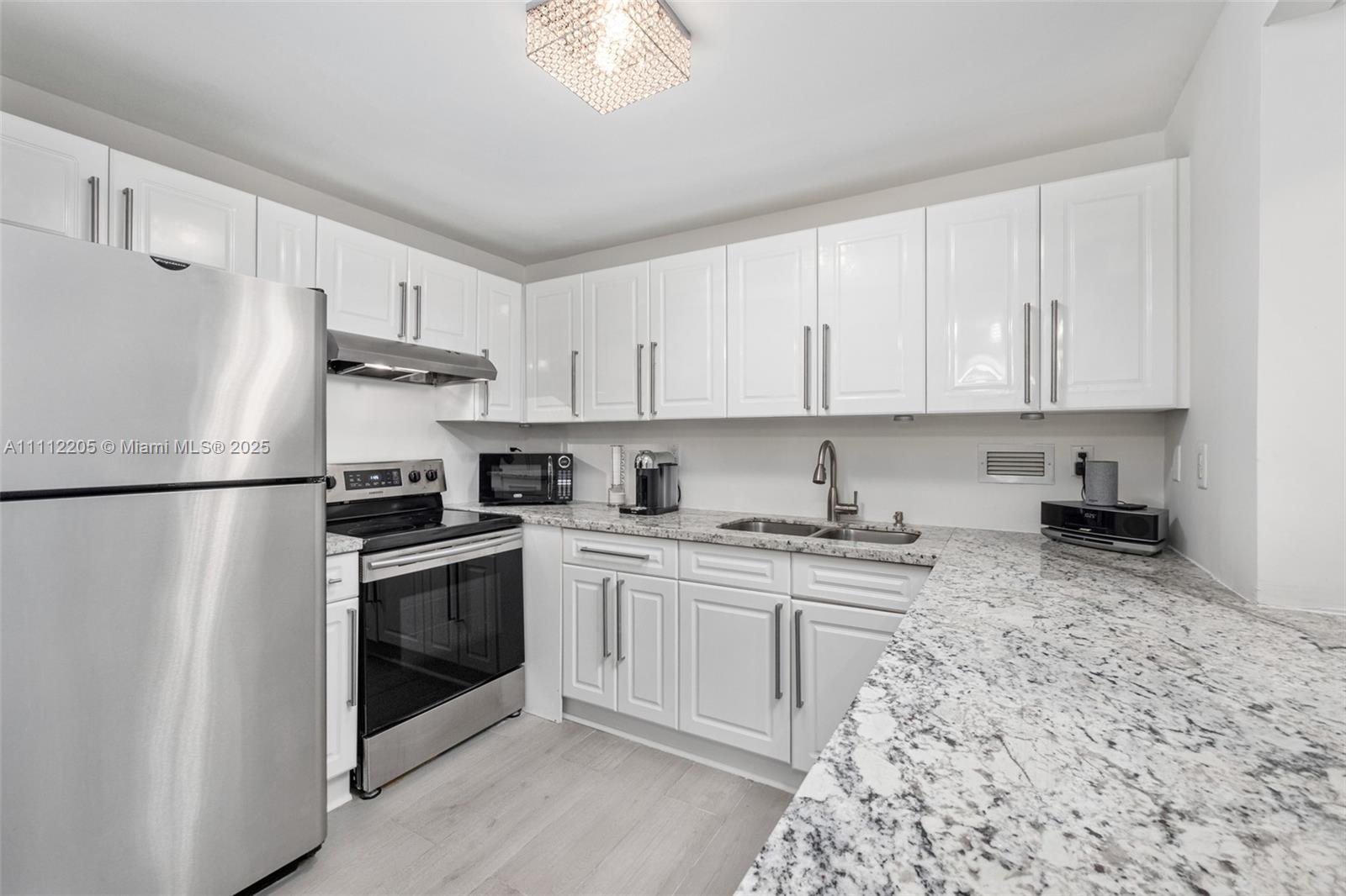 A kitchen features white cabinets, granite countertops, and stainless steel appliances — 2301 Collins Ave # 328, Miami Beach FL 33139, MIAMI BEACH, FL