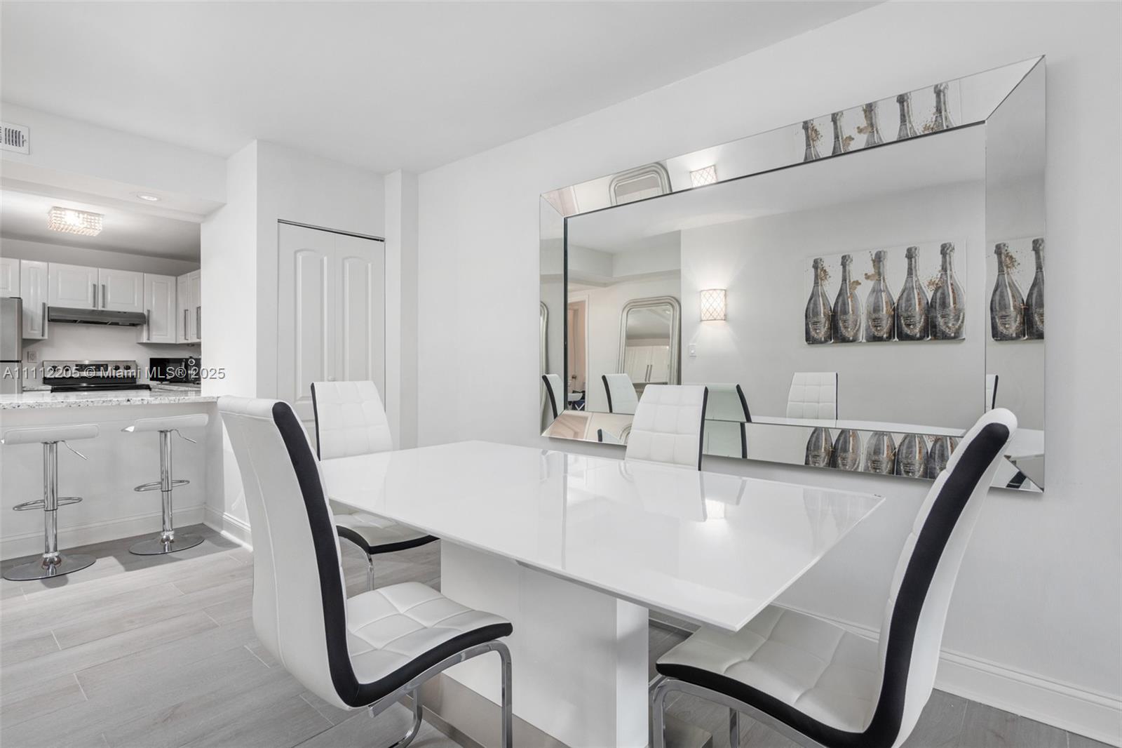 A dining area features a white table, four modern chairs, and a large wall mirror — 2301 Collins Ave # 328, Miami Beach FL 33139, MIAMI BEACH, FL
