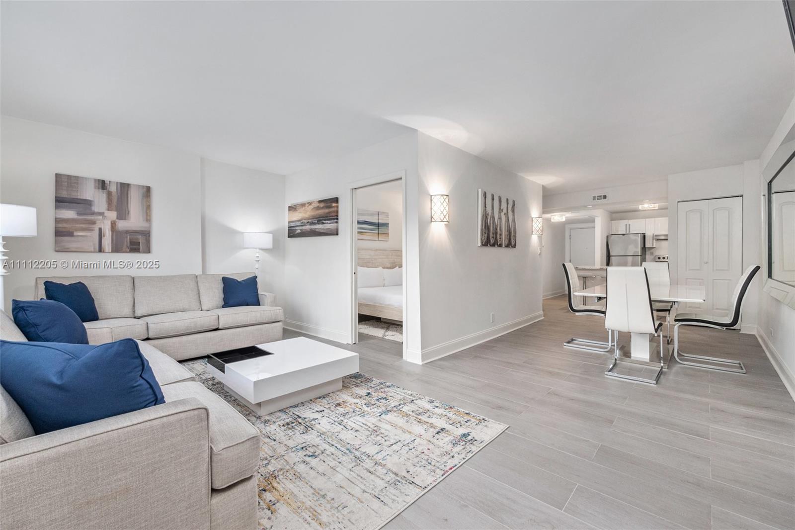A modern living and dining area features light wood-look tile floors and neutral furniture — 2301 Collins Ave # 328, Miami Beach FL 33139, MIAMI BEACH, FL