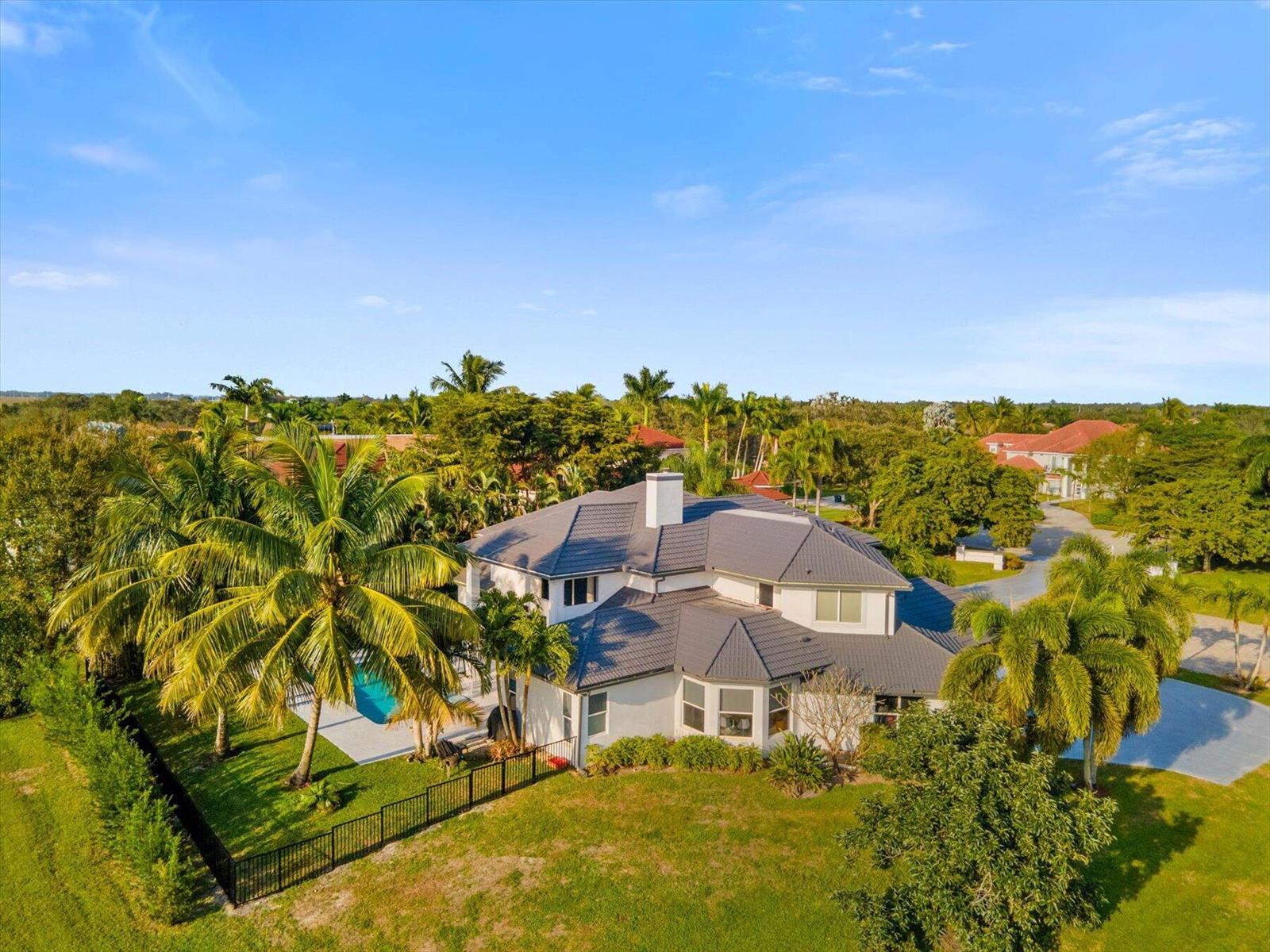 An aerial view of a two-story house with a grey roof, pool, and palm trees — 2135 Windsock Way, Wellington FL 33414, WELLINGTON, FL