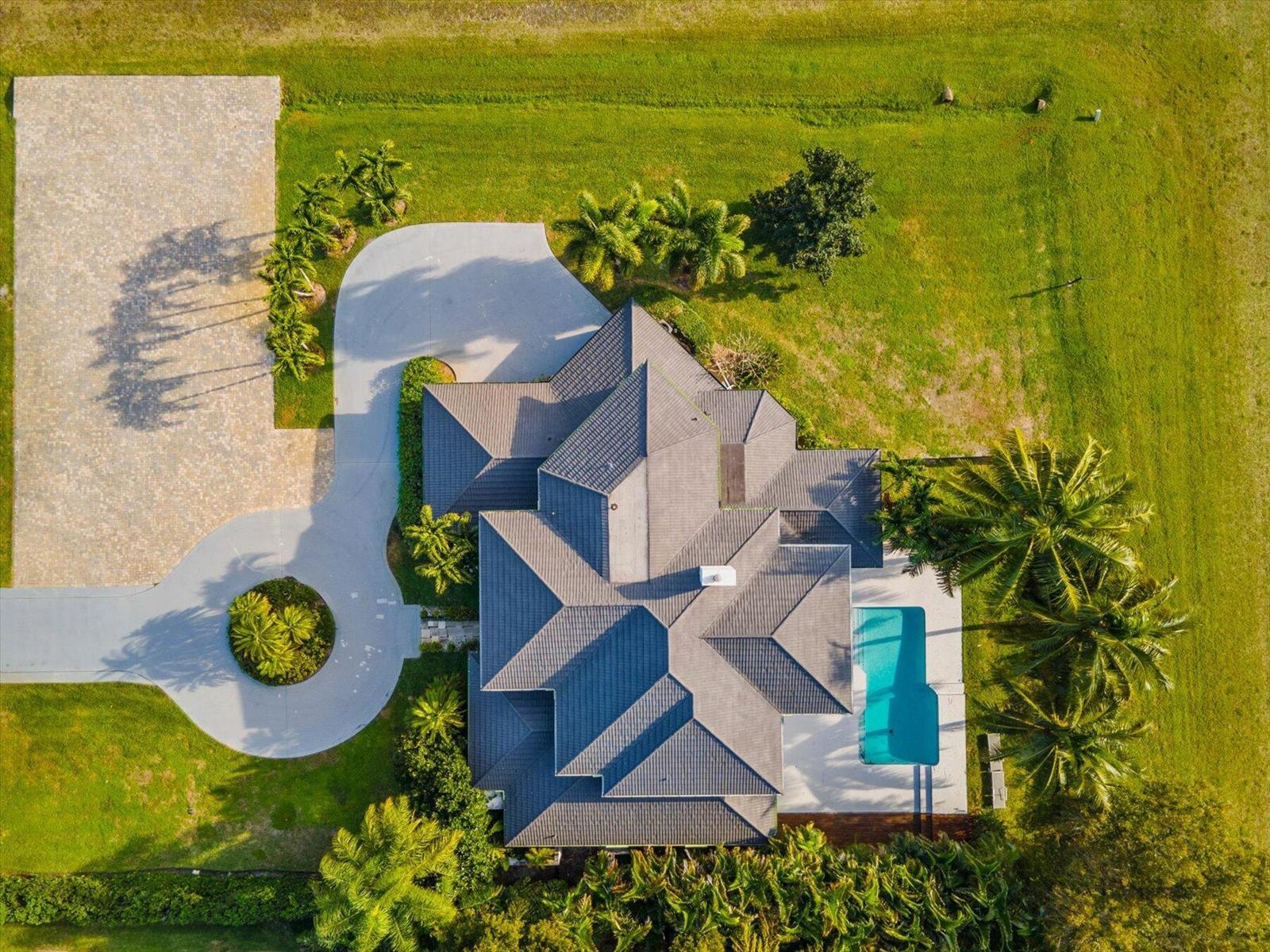 An aerial view shows a house with a dark tiled roof, a pool, and a driveway — 2135 Windsock Way, Wellington FL 33414, WELLINGTON, FL