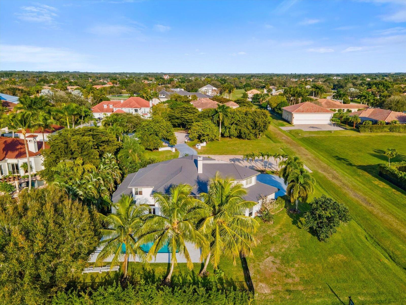 An aerial view of a suburban house with a pool, palm trees, and large lawn — 2135 Windsock Way, Wellington FL 33414, WELLINGTON, FL
