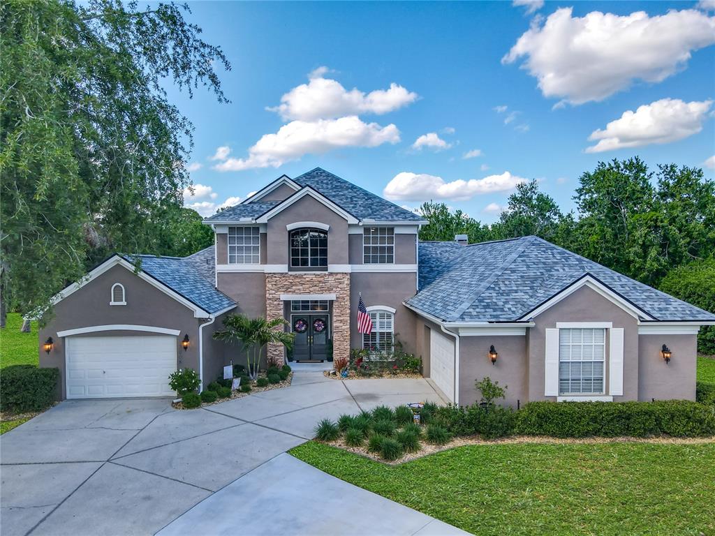 A two-story suburban house with a stone facade, gray exterior, and a multi-car garage — 3008 SUTTON WOODS DRIVE, PLANT CITY, FL