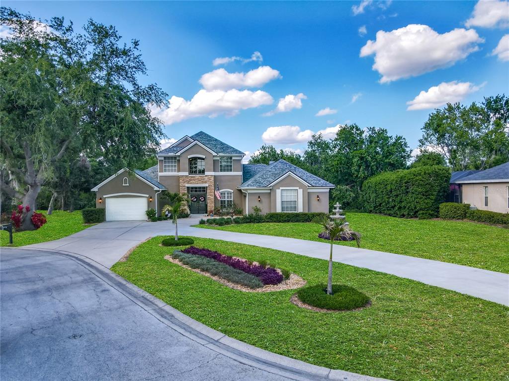 A two-story suburban house with a concrete driveway, manicured lawn, and a stone-accented entryway — 3008 SUTTON WOODS DRIVE, PLANT CITY, FL